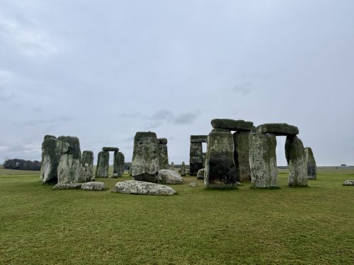 Stonehenge ancient stone circle monument on green grass field under cloudy sky in Wiltshire, England