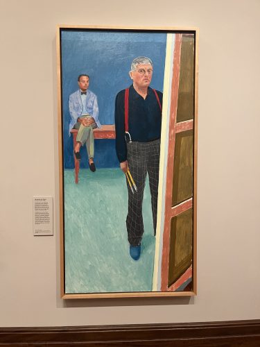 Framed painting showing two men in an interior space - one seated in blue suit, one standing in dark sweater and plaid pants