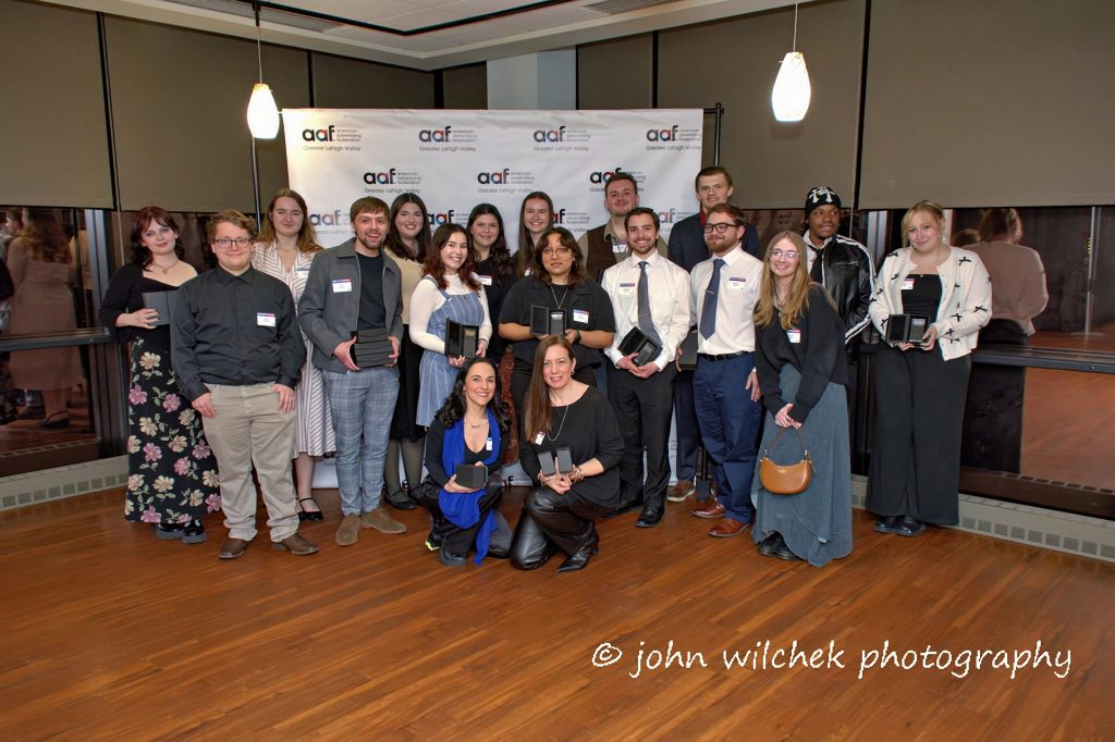 Group of award recipients holding plaques posing at AAF advertising awards ceremony in modern conference room